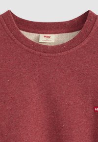 Rode sweatshirt met een ronde hals, gemaakt van textuurstof met een gespetterd patroon. Kleine merklabel op de linker voorkant.