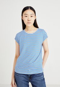T-shirt à rayures bleues et blanches à manches courtes avec un col rond, fabriqué en tissu doux, associé à un jean en denim bleu.