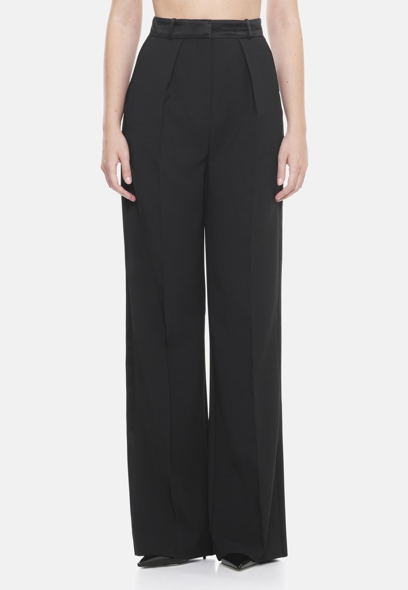 Pantalones de pierna ancha negros con una cintura alta, frente plisado y tejido suave. El diseño incluye pasadores para cinturón y un ajuste entallado.