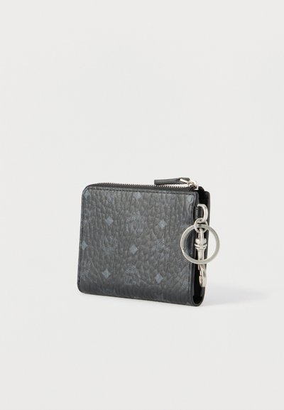 Μαύρο πορτοφόλι από υφή δέρματος με διακριτικό μοτίβο λογότυπου, ασημένιο κρίκο για κλειδιά και κλείσιμο με φερμουάρ σε ουδέτερο φόντο.