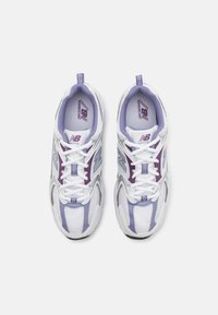 White athletic shoes with purple accents and mesh panels. Features a lace-up design, padded collar, and New Balance branding on the tongue.