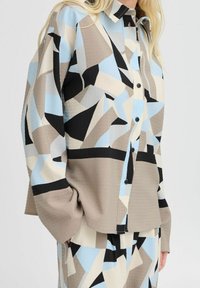 Overhemd met knoopsluiting en een geometrisch patroon in lichtblauw, beige, zwart en crèmekleur; lichtgewicht stof met een gestructureerde afwerking en een relaxte pasvorm.