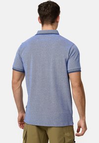 Polo bleu à manches courtes en tissu texturé, avec des finitions contrastantes en marine sur le col et les poignets.