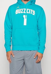 Felpa turchese con tasca frontale, caratterizzata dalla scritta "BUZZ CITY" in grassetto bianco e un piccolo logo sulla spalla.