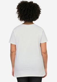 Hvid bomulds t-shirt med korte ærmer, en afslappet pasform og rund halsudskæring. Glat tekstur uden synlige mønstre eller detaljer.