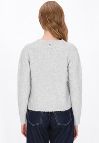 Grå uldtrøje med rund hals, let cropped kant og lange ærmer. Blød tekstur, minimalistisk design og et lille mærke bagpå.