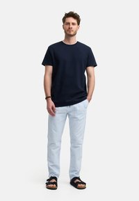 Camiseta de algodón azul marino, pantalones a cuadros azul claro y sandalias negras. Estilo sencillo y relajado con un corte cómodo y escote redondo.