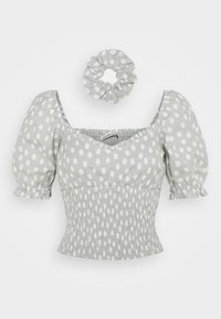 Top gris con lunares y mangas abullonadas, con detalles fruncidos, junto a una diadema a juego. Tejido de algodón suave, diseño de escote cuadrado.