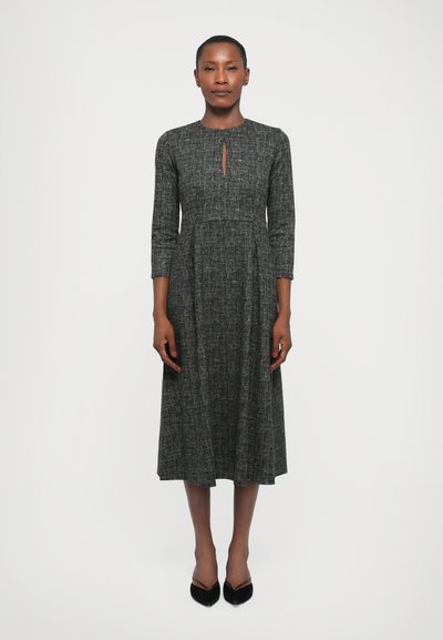 Black and grey patterned dress with three-quarter sleeves, round neckline, and a keyhole detail at the front. Flowing A-line silhouette.