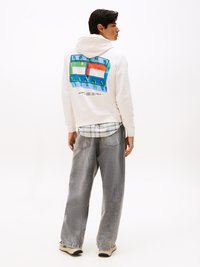 Hoodie alb cu un grafic rectangular colorat pe spate, care include text, asortat cu blugi gri lejeri și adidași.