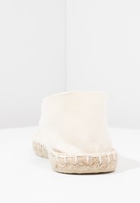 Weiße Leinenschuh-espadrille mit einer gewebten Juteksohle, die ein schlichtes, sauberes Design und eine abgerundete Rückseite aufweist. Strukturierte Stoffoberfläche.