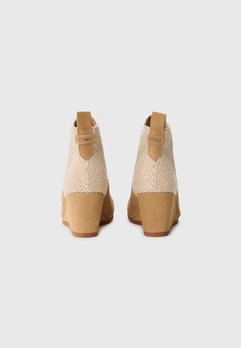 Bottines beiges à cheville avec un dessus en tissu texturé de chevrons tissé, des accents en daim, un talon bloc et une languette à l'arrière.