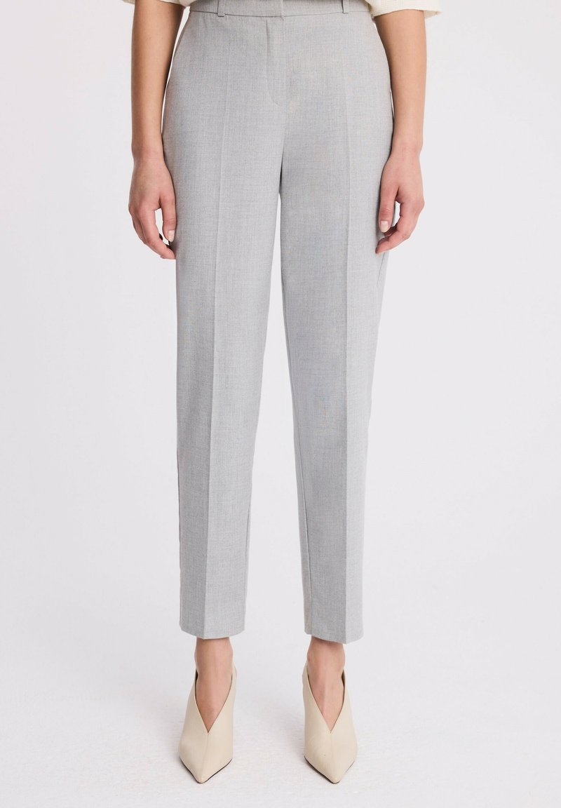 Jasnoszare dopasowane spodnie o prostym kroju, z wyraźnymi liniami z przodu i gładką fakturą, w połączeniu z beżowymi szpilkami w kształcie spiczastym.
