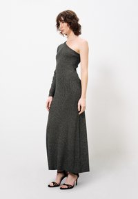 Een een-schouder, vloerlange jurk in het zwart met een metallic glans; geribbelde textuur; voorzien van een lange mouw aan één kant en een getailleerde silhouet.