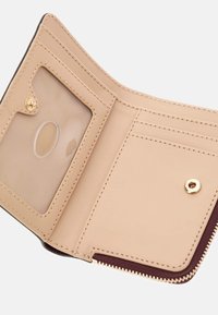 Cartera de cuero beige plegada con compartimento transparente para identificación, múltiples ranuras para tarjetas, cierre con botón a presión y un compartimento con cremallera parcialmente visible.