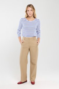 Gestreiftes langärmliges Hemd mit blauen und weißen Streifen, kombiniert mit beigen Hosen. Das Model trägt rote Ballerinas. Einfaches, gerades Design.
