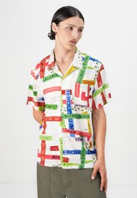 Short-sleeve button-up shirt made of lightweight fabric, featuring a multicolored patchwork design with various prints and patterns.