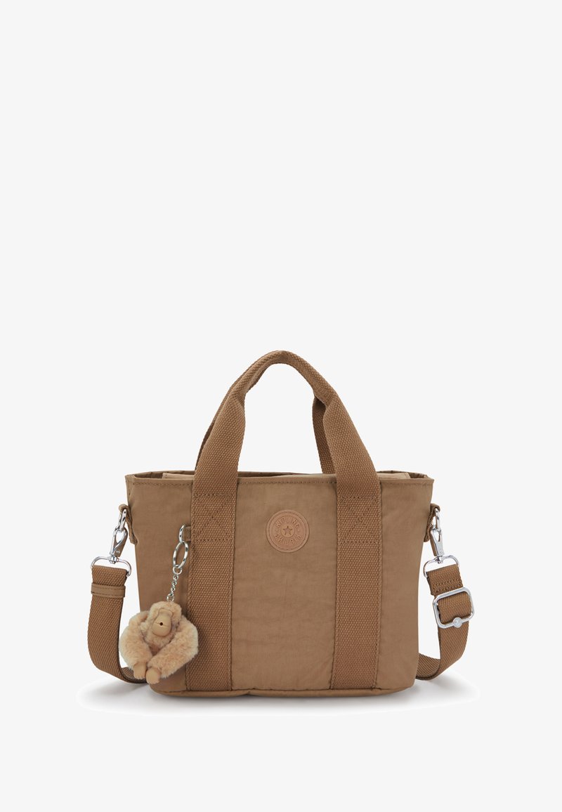 Braune Stofftasche mit breiten Griffen, verstellbarem Schulterriemen, runder geprägter Logo und einem flauschigen Affen-Schlüsselanhänger, der an der Seite befestigt ist.