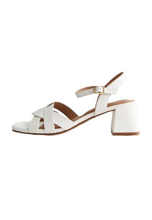 Witte leren sandaal met open teen, gekruiste banden, enkelgesp en blokhak op een witte achtergrond.