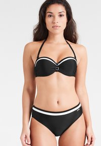 Zwarte bikini bovenkant met onderdraden, witte accentstrepen en gespsluiting; bijpassende zwarte high-waisted broekjes met een witte tailleband.