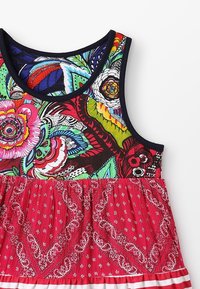 Kolorowa sukienka bez rękawów z kwiatowym topem i spódnicą w czerwony wzór bandany, wykonana z fakturowanej tkaniny z czarnymi wykończeniami.