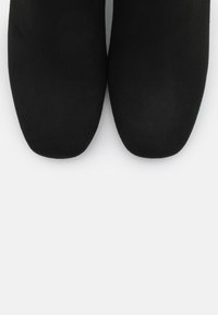 Czarne płaskie buty z gładkim, matowym wykończeniem. Okrągły czubek i brak widocznych elementów metalowych czy ozdób. Prosty i elegancki kształt.