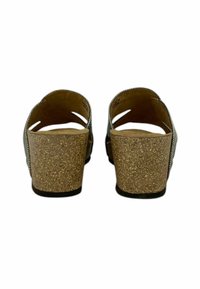 Sandali con tacco in sughero e apertura sul retro, caratterizzati da una parte superiore testurizzata e due cinturini diagonali. Il tacco è alto circa cinque centimetri.