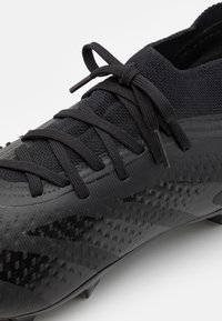 Scarpa da calcio nera con tomaia sintetica testurizzata, dotata di collare a maglia rigida e lacci piatti, punta rinforzata e tacchetti rimovibili.