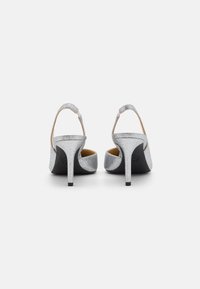 Sandales à talons hauts argentées avec une finition scintillante, dos ouvert et design à talon fin. Comprend une fine bride de cheville et un intérieur rembourré.