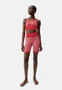 Rotes sportliches Set aus strukturiertem Stoff; beinhaltet ein kurzes Tanktop mit breiten Trägern und hochgeschnittene Shorts mit weißen Nähten.
