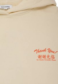 Sudadera con capucha de color crema y textura suave, con texto impreso en naranja: "¡Gracias!" y "No se aceptan cheques, por favor." con caracteres chinos.