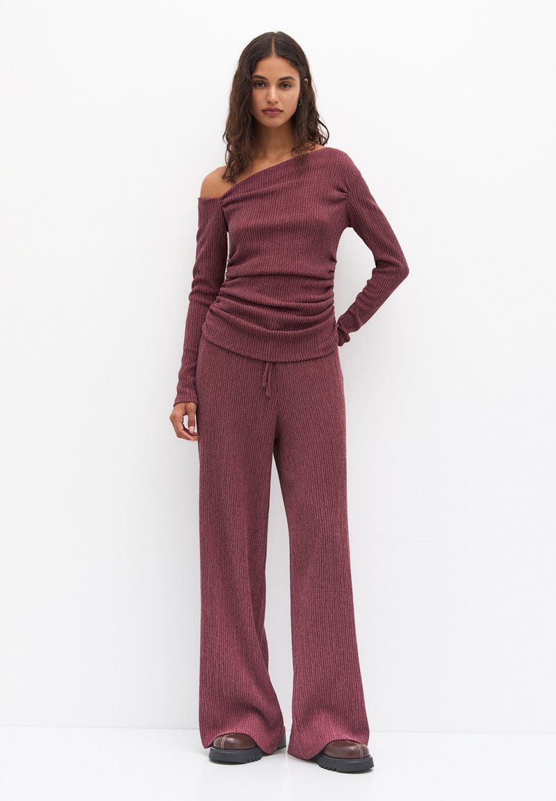 Set a due pezzi a coste color bordeaux, composto da una maglietta a maniche lunghe e scollo off-shoulder e pantaloni a gamba larga con vita regolabile tramite coulisse. Tessuto strutturato.