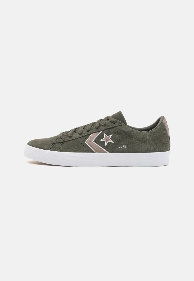 Baskets basses en daim vert olive avec semelle blanche, logo étoile chevron rose et blanc, et texte "CONS" sur le côté.