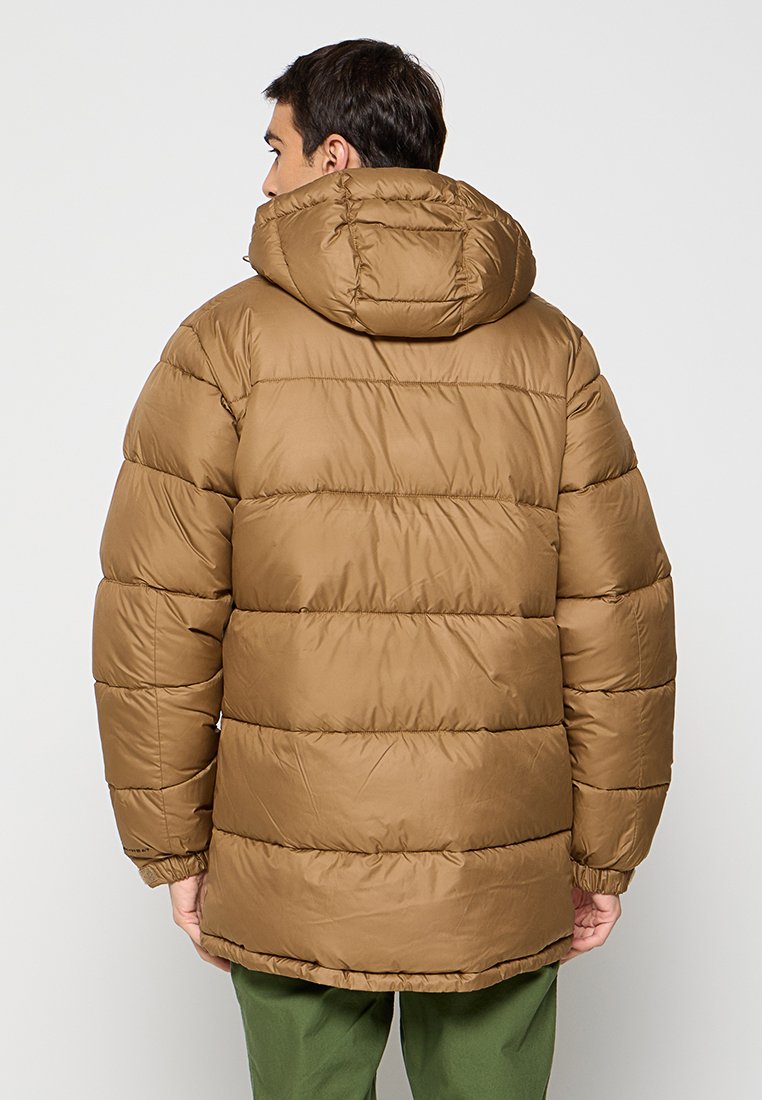 Veste matelassée marron avec capuche, présentant un design matelassé et des poignets élastiques. Le matériau semble lisse et résistant à l'eau.