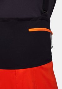 Section supérieure noire avec poche zippée orange, se dégradant vers une section inférieure orange vif. Texture lisse, design fonctionnel avec des sangles réglables.