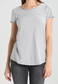 Grå bomullströja med kort ärm, rund halsringning och en liten logotyp på bröstet. Mjuk textur och vanlig passform med en svagt rundad nederkant.