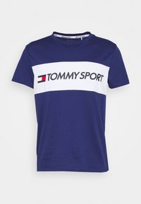 Marinblå bomullströja med en vit horisontell rand med texten "TOMMY SPORT", rund halsringning och korta ärmar.