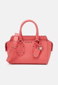 Sac à main en cuir corail avec deux poignées, une sangle détachable, des accessoires en argent, des clous décoratifs et une étiquette attachée avec un cadenas.