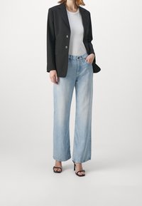 Musta räätälöity bleiseri, jossa kaksi nappia, vaaleanharmaa vartalonmyötäinen paita ja leveälahkeiset vaaleansiniset farkut, yhdistettynä mustiin korkokenkiin.