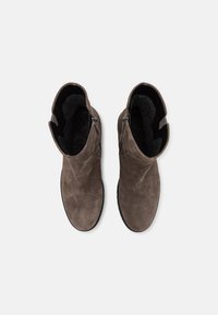 Botines de ante marrón con un interior suave y peludo, que cuentan con una cremallera lateral y un diseño de punta redondeada.