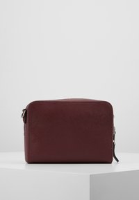Obdélníková kabelka v barvě burgundské červené z texturované kůže, s uzávěrem na zip a stříbrnými kovovými doplňky. Jednoduchý design bez viditelných log.
