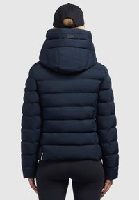 Donkerblauwe gewatteerde jas met een hoge kraag en een capuchon, voorzien van een doorgestikt ontwerp en een logo-accent op de achterkant.