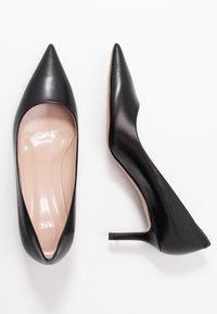 Décolleté nero in pelle con punta affusolata e finitura lucida, soletta nude e tacco quadrato basso. Design semplice, senza modelli o accenti visibili.