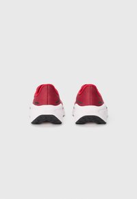 Chaussures de sport rouges avec tige en maille, semelle intermédiaire rembourrée blanche et semelle extérieure en caoutchouc noire. Présente un design minimaliste et un rembourrage doux au niveau du talon.