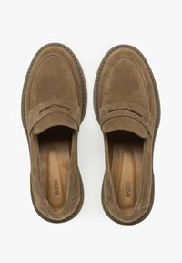 Bruine suède instappers met een moccasinontwerp, voorzien van stikdetails en een getextureerde rubberen zool. Glad interieurvoering zichtbaar.
