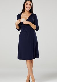 Navy dress with a V-neck and three-quarter sleeves, stretchy fabric, empire waist, knee-length, showcasing a smooth texture.