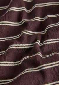 Brunt strikket stof med jævnt fordelte tynde hvide vandrette striber og synlige teksturfolder.