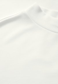 Camiseta blanca con un escote redondo alto, textura suave y un diseño minimalista con un sutil detalle acanalado en el cuello.