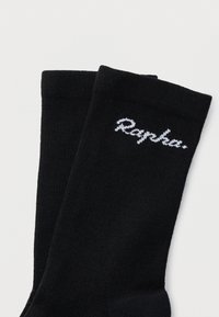 Μαύρες κάλτσες από μαλακό υλικό με ριμπ ύφανση και λευκό λογότυπο "Rapha." κεντημένο στο πλάι. Ομαλή υφή σε όλη την επιφάνεια.