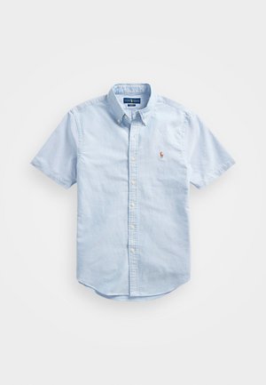 Šviesiai mėlyna trumpa rankovė marškiniai iš medvilnės audinio. Yra mygtukų žemyn krūtinės srityje, mygtukas ant apykaklės ir siuvinėtas logotipas ant krūtinės.